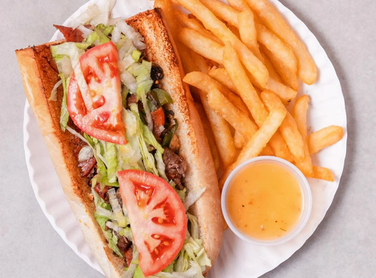 Sous-marin au steak avec laitue et tomate, servi avec frites et sauce