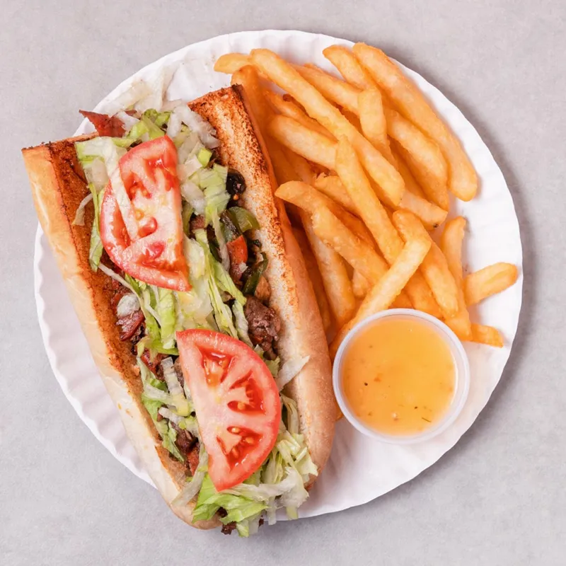 Steak submarine with lettuce and tomato, served with fries and sauce