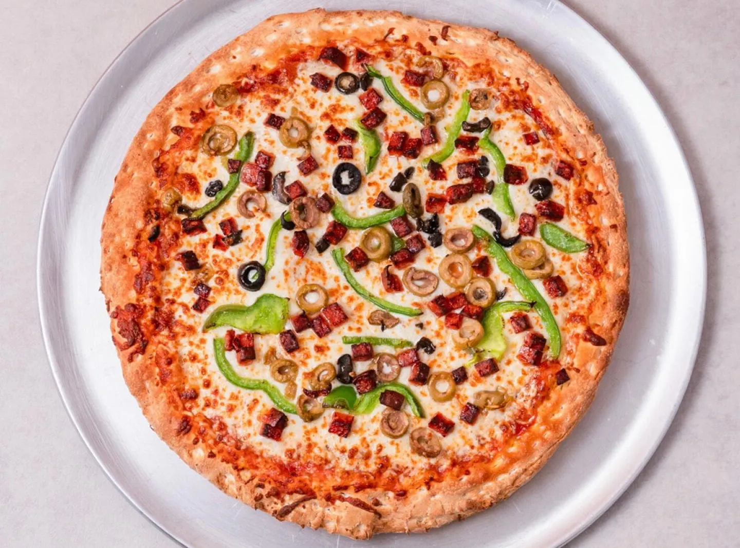 Pizza toute garnie avec pepperoni, champignons, poivrons verts et olives noires